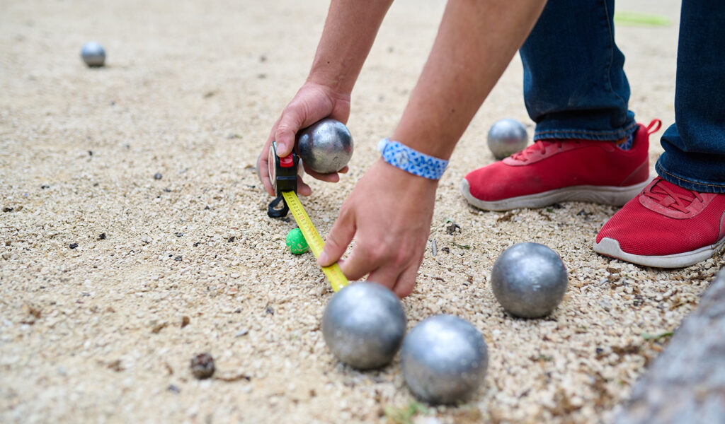 Nachbarn beim gemeinsamen Boule-Spielen in Ludwigsburg – Nahaufnahme einer Abstandsmessung auf dem Bouleplatz.